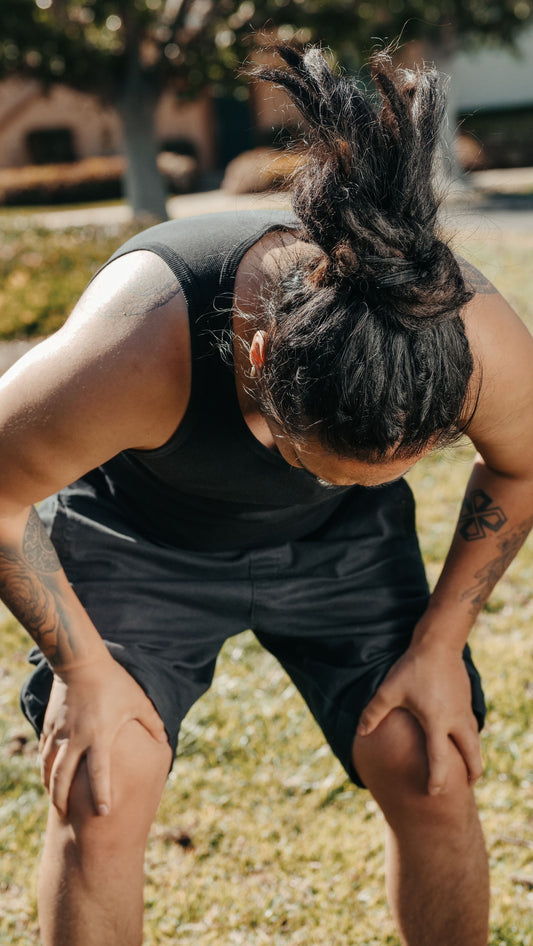 A man holding his knee after training — the moment something goes, usually weeks after coming back